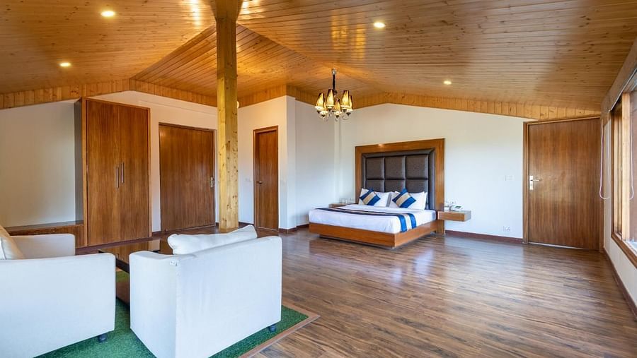 A wide angle shot of the suite featuring king size bed, wooden furnishing and a seating area  | DLS Serenity Resort and Spa